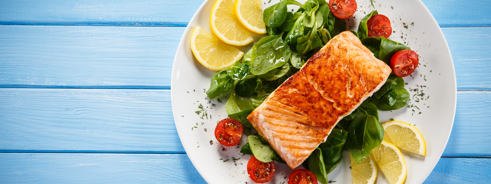 Grilled salmon with French fries and vegetables on wooden table