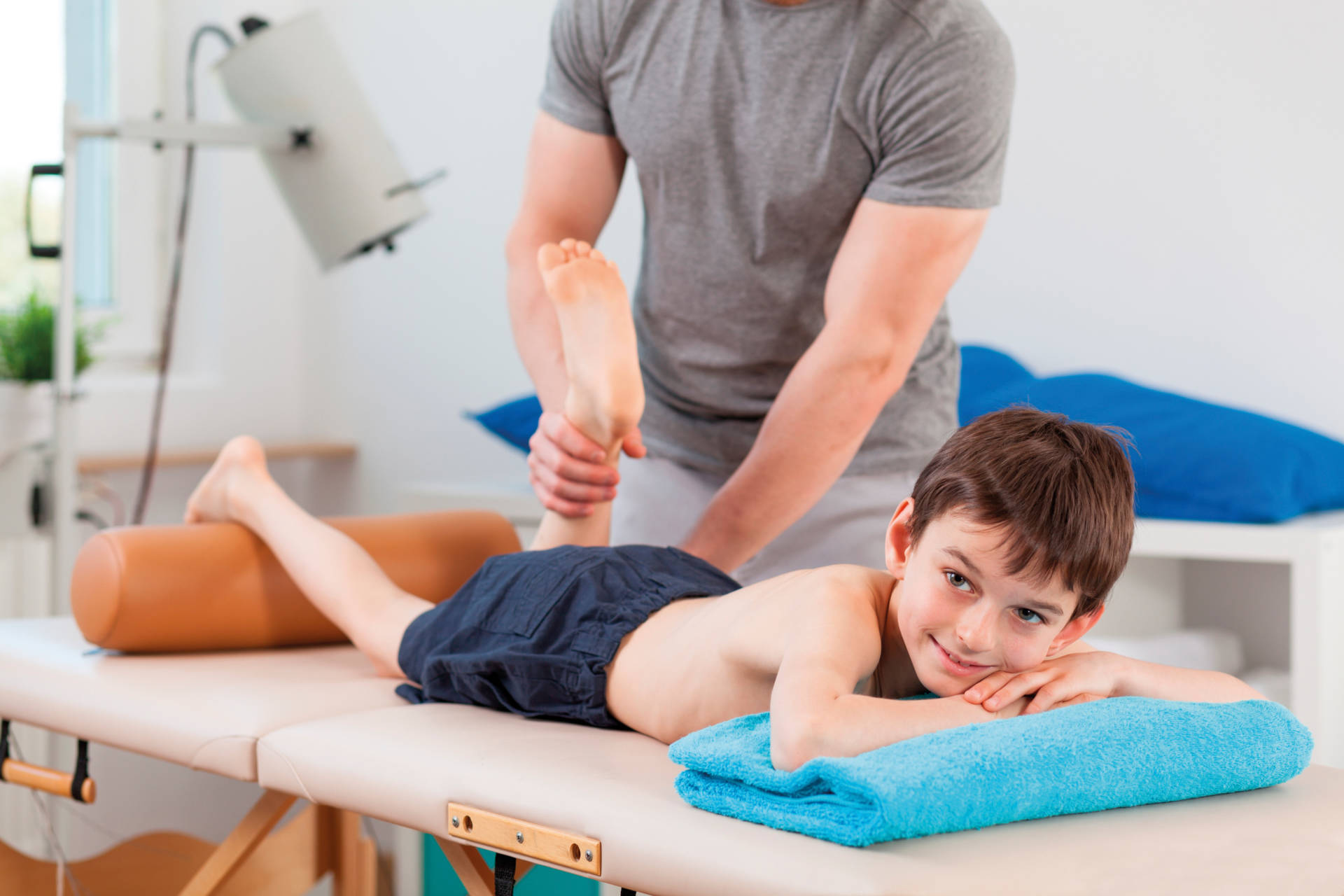 Boy lying on physiotherapy table and having a leg massage